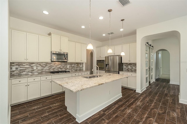 kitchen with dark wood-type flooring, a center island with sink, stainless steel appliances, and sink