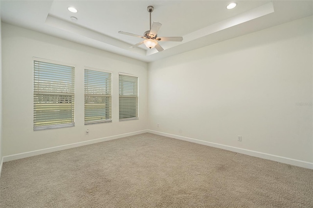 spare room featuring carpet floors, a raised ceiling, and ceiling fan