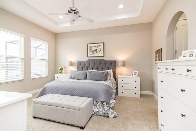 carpeted bedroom featuring a raised ceiling and ceiling fan