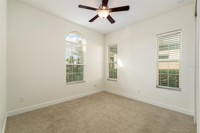 carpeted spare room with ceiling fan and plenty of natural light