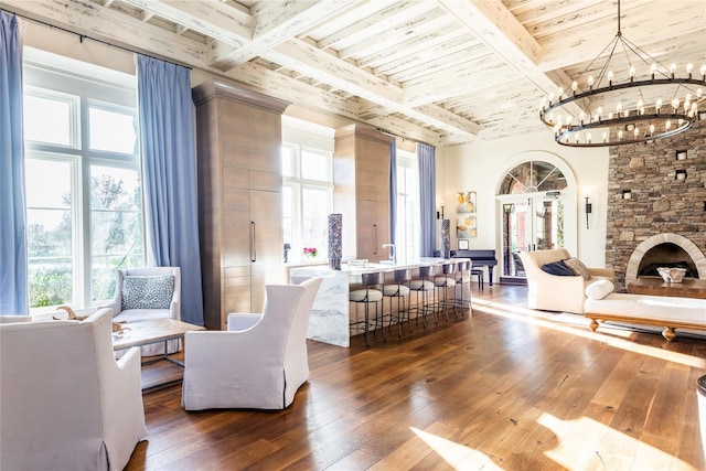 interior space featuring dark hardwood / wood-style floors, beam ceiling, and a stone fireplace