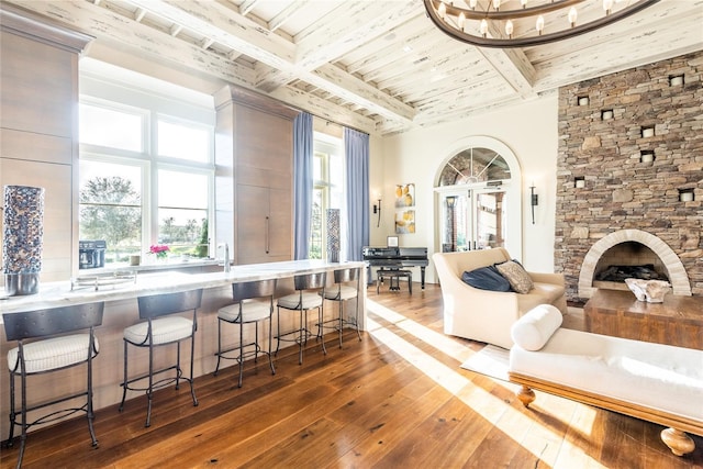 interior space featuring beamed ceiling, hardwood / wood-style floors, a stone fireplace, and wooden ceiling