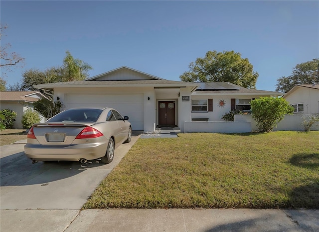 ranch-style home with a garage, a front yard, and solar panels