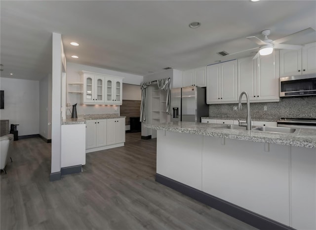 kitchen with white cabinets, appliances with stainless steel finishes, dark hardwood / wood-style floors, and light stone counters