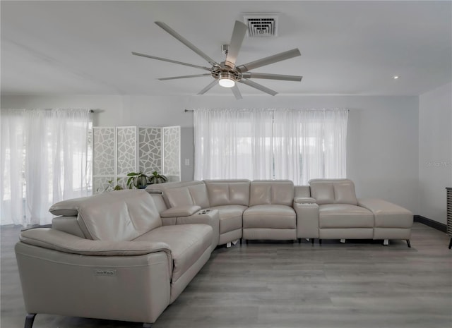 living room with light wood-type flooring, a wealth of natural light, and ceiling fan