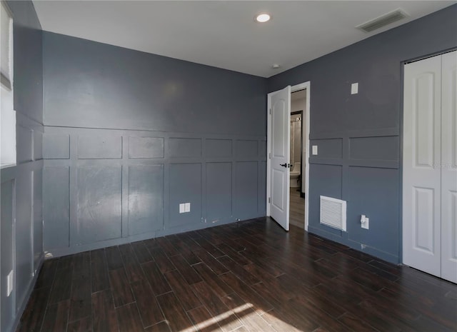 unfurnished bedroom with dark hardwood / wood-style floors and a closet