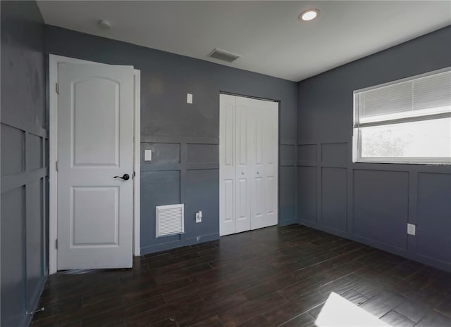 unfurnished bedroom featuring a closet and dark wood-type flooring