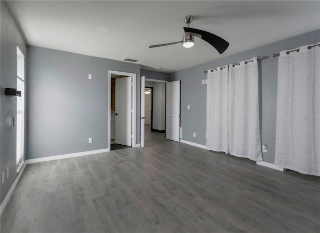 unfurnished room with a wealth of natural light, ceiling fan, and dark wood-type flooring