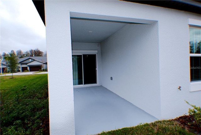 property entrance featuring a lawn and a patio