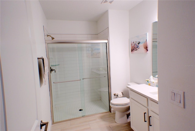 bathroom with hardwood / wood-style flooring, vanity, an enclosed shower, and toilet