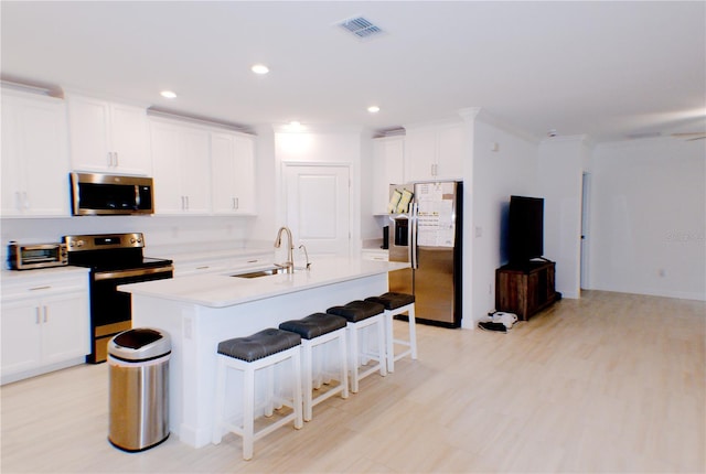 kitchen with a kitchen island with sink, sink, white cabinets, and appliances with stainless steel finishes