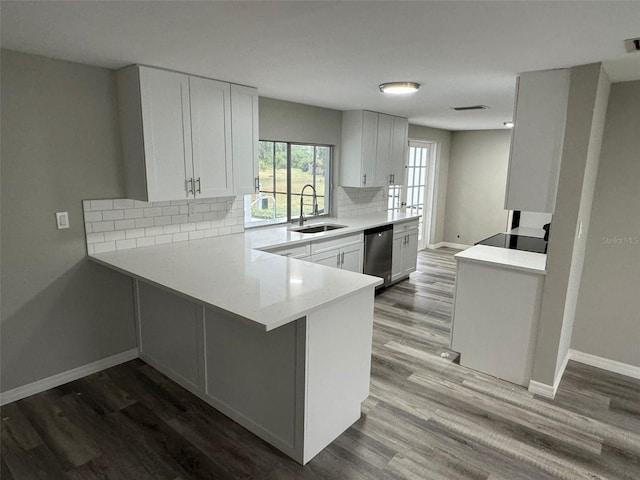 kitchen featuring kitchen peninsula, sink, wood-type flooring, dishwasher, and white cabinetry