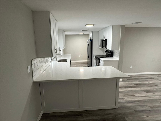 kitchen with white cabinets, kitchen peninsula, sink, and appliances with stainless steel finishes