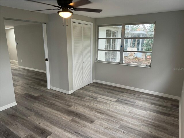 unfurnished bedroom with dark hardwood / wood-style flooring, a closet, and ceiling fan