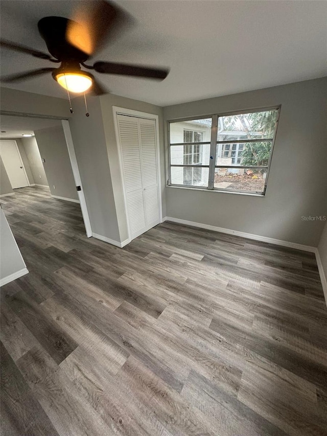 unfurnished bedroom with ceiling fan, dark wood-type flooring, and a closet