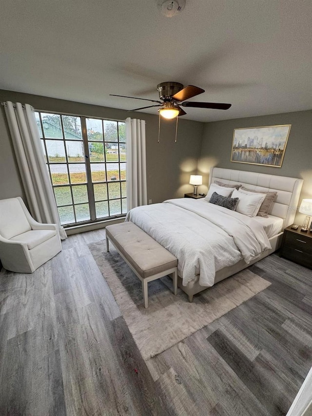 bedroom with hardwood / wood-style flooring, ceiling fan, and a textured ceiling