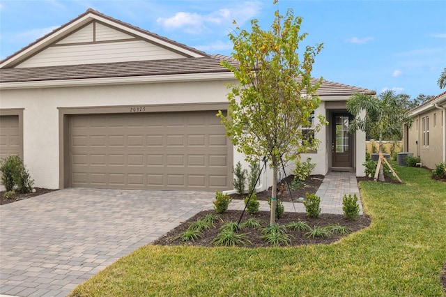 view of front of house with a garage, central air condition unit, and a front lawn