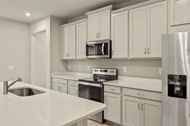 kitchen with appliances with stainless steel finishes, sink, and white cabinets