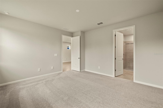 unfurnished bedroom featuring ensuite bathroom and light carpet