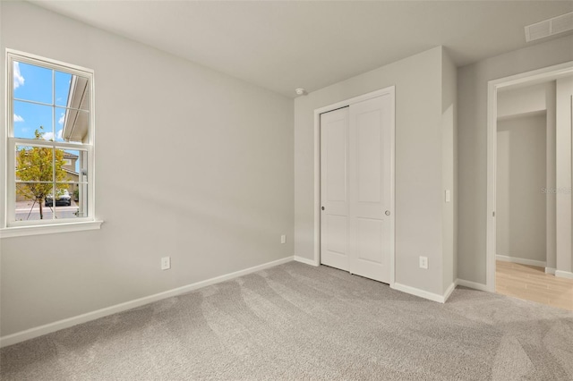 unfurnished bedroom featuring light colored carpet and a closet