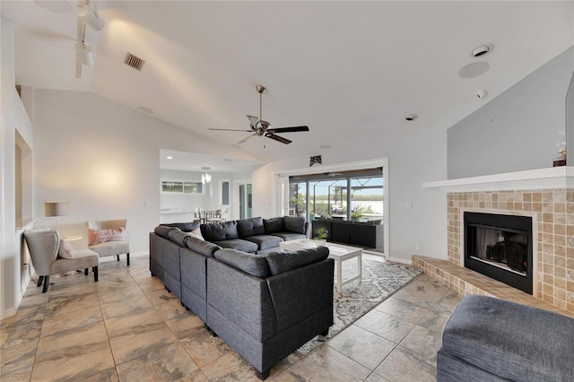 living room featuring ceiling fan, lofted ceiling, and a tile fireplace