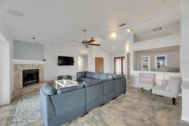 living room with ceiling fan, a fireplace, and vaulted ceiling