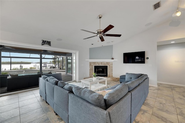 living room with a tiled fireplace, ceiling fan, and lofted ceiling