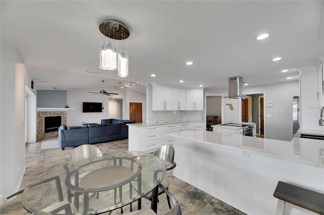 dining room featuring ceiling fan, lofted ceiling, sink, and a brick fireplace