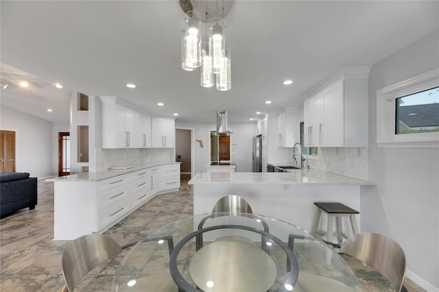 kitchen featuring white cabinets, sink, stainless steel fridge, tasteful backsplash, and kitchen peninsula