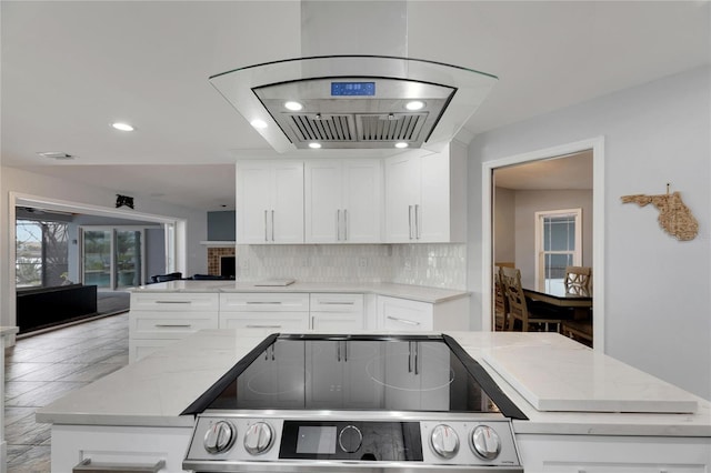 kitchen with decorative backsplash, white cabinetry, and stove