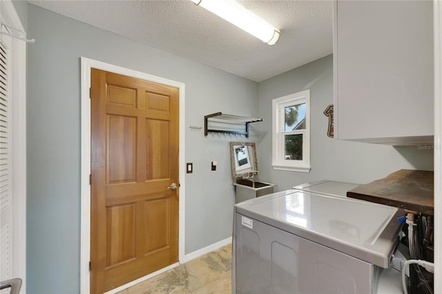 clothes washing area with cabinets, washing machine and dryer, and a textured ceiling