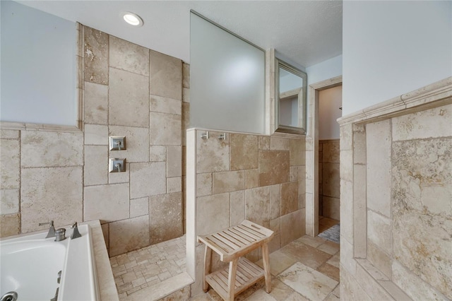 bathroom with tile walls and shower with separate bathtub