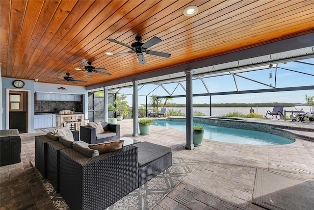 view of swimming pool with an outdoor kitchen, a patio area, and a lanai