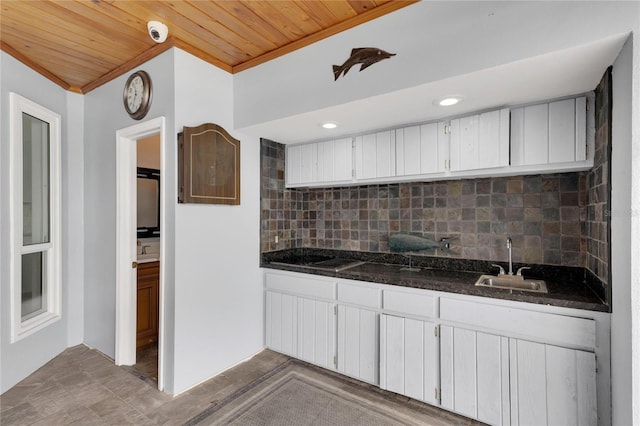 kitchen with wooden ceiling, backsplash, crown molding, sink, and white cabinetry