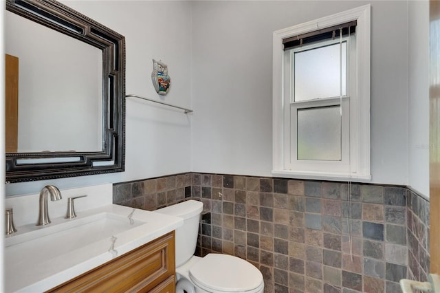 bathroom with vanity, toilet, and tile walls