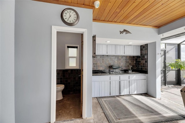 kitchen with backsplash, white cabinetry, sink, and wood ceiling