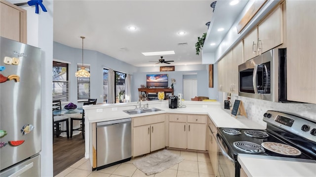 kitchen featuring light brown cabinets, sink, a skylight, kitchen peninsula, and stainless steel appliances