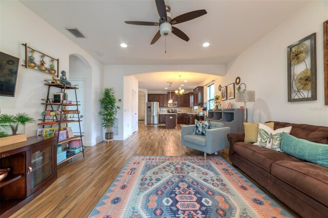 living room with dark wood-type flooring and ceiling fan with notable chandelier