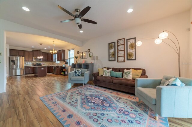 living room with ceiling fan with notable chandelier and wood-type flooring