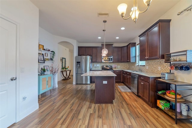 kitchen featuring decorative light fixtures, a kitchen island, light hardwood / wood-style floors, and stainless steel appliances