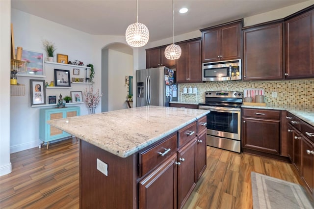 kitchen with pendant lighting, dark hardwood / wood-style floors, decorative backsplash, appliances with stainless steel finishes, and a kitchen island