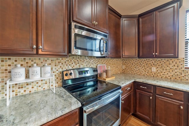 kitchen with light stone countertops, stainless steel appliances, and tasteful backsplash