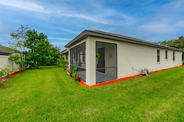 back of house featuring a yard and a sunroom