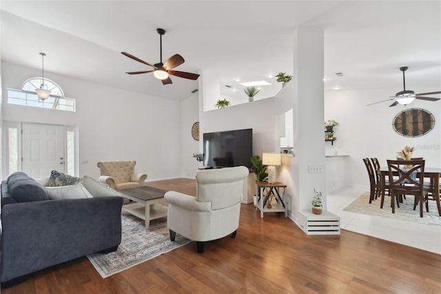 living room with a high ceiling, a ceiling fan, and dark wood-type flooring