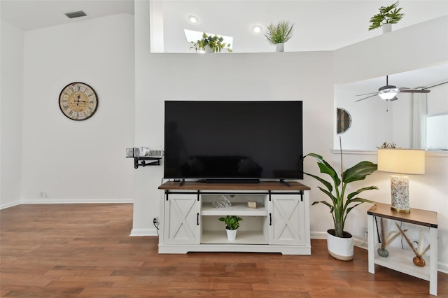 living room featuring a ceiling fan, baseboards, visible vents, and wood finished floors