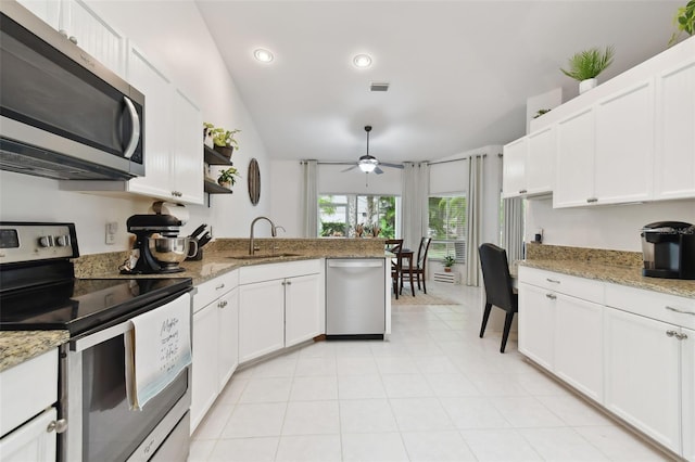 kitchen with appliances with stainless steel finishes, light stone counters, a peninsula, white cabinetry, and a sink