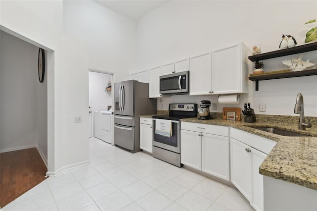 kitchen with white cabinets, stone countertops, stainless steel appliances, and a sink