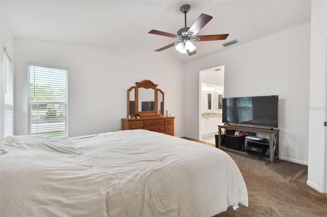 carpeted bedroom with ensuite bathroom, a ceiling fan, visible vents, vaulted ceiling, and baseboards