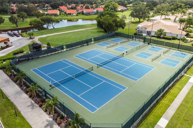 view of tennis court featuring a water view, fence, and a residential view