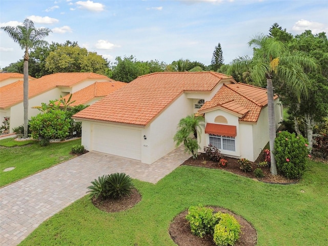 mediterranean / spanish house with driveway, a tiled roof, an attached garage, a front lawn, and stucco siding